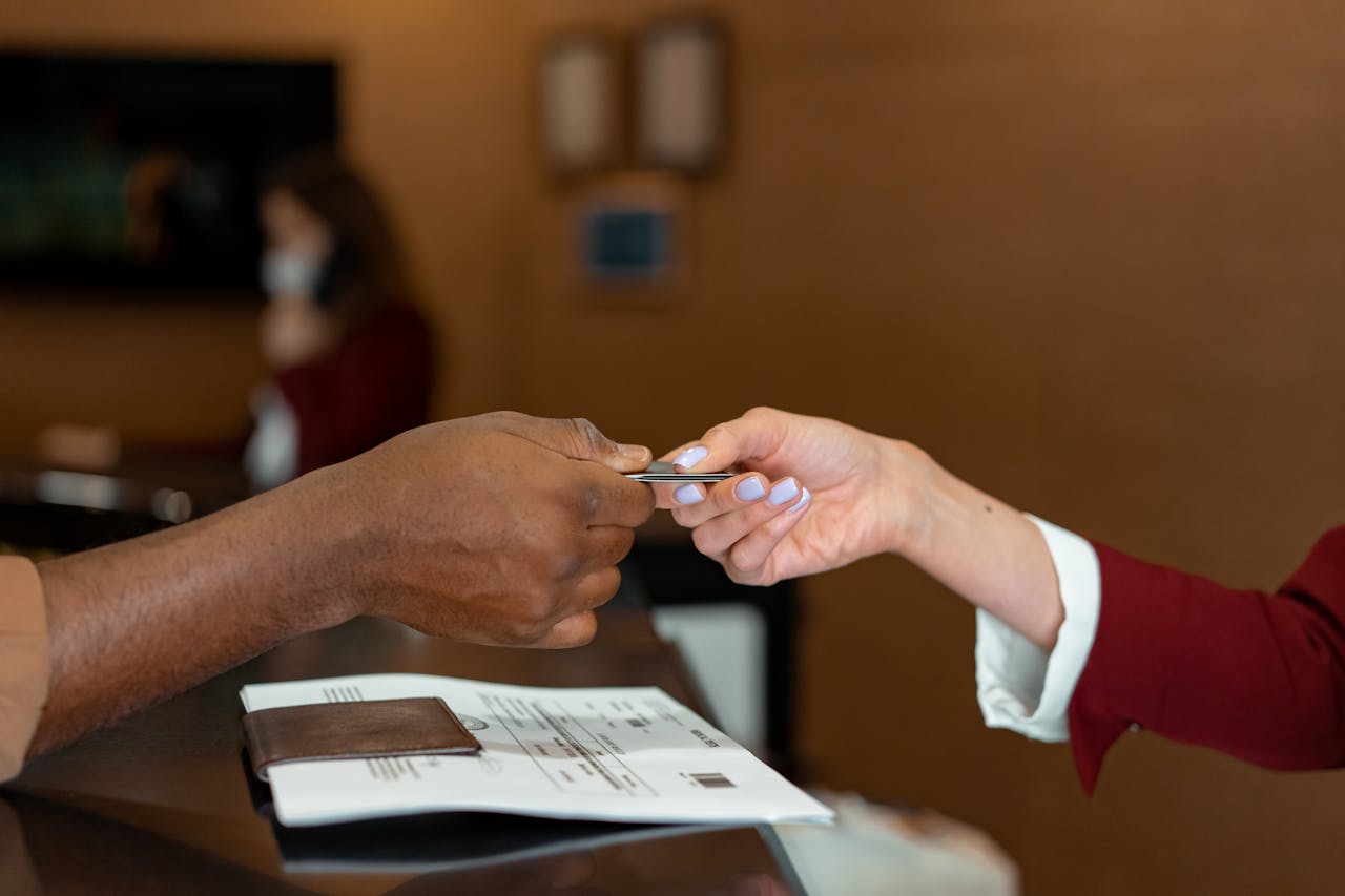 Close-up of a hotel receptionist receiving a credit card from a guest, highlighting a transaction at check-in.
